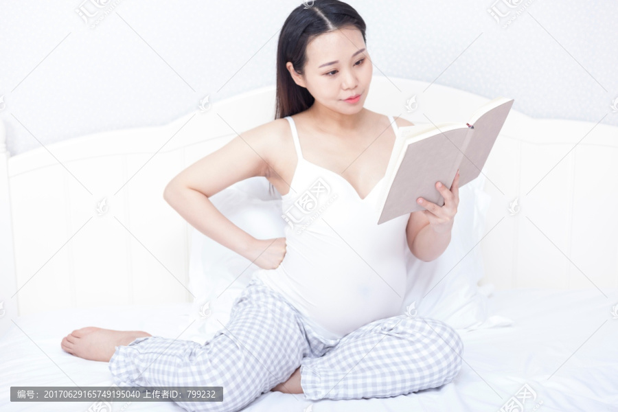 孕妇坐在床上看书