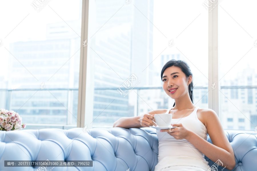年轻女子在沙发上喝咖啡