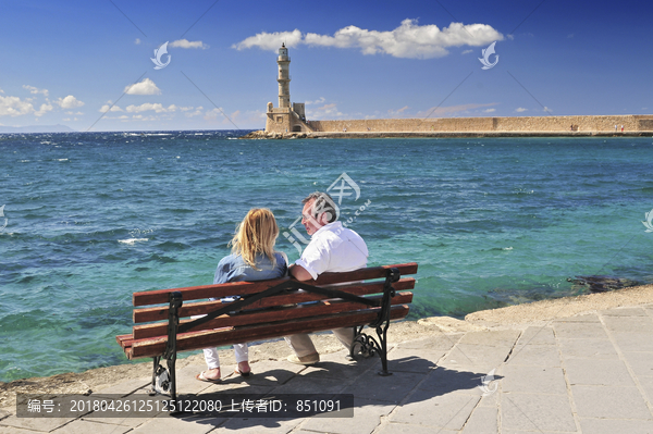 旧威尼斯港灯塔前长椅坐着的夫妇