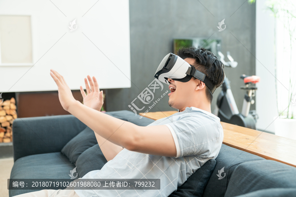 年轻男子在沙发上使用VR眼镜