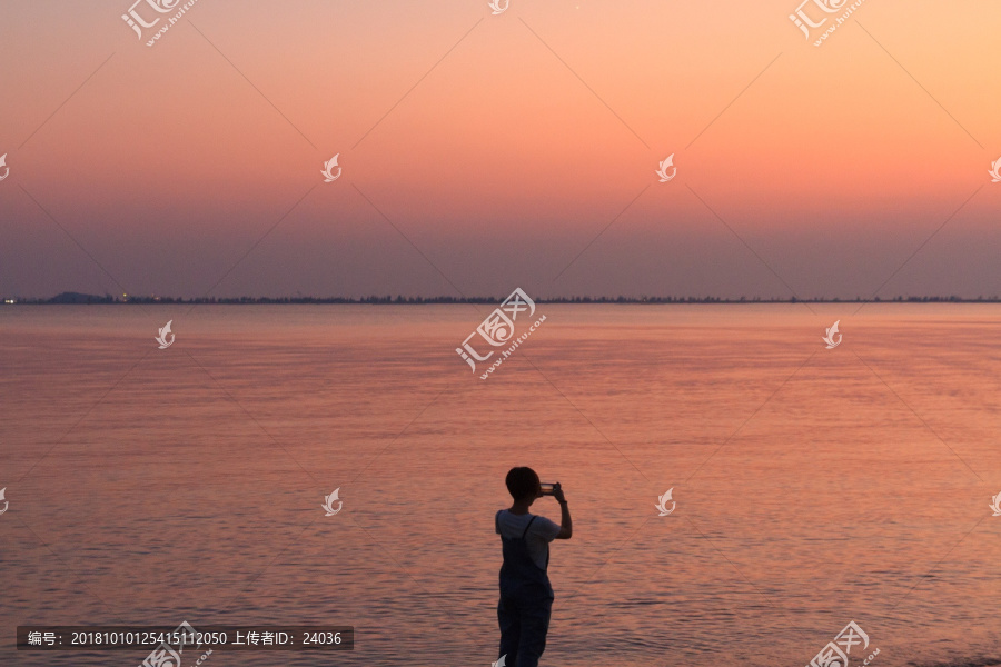 海滨黄昏风光用手机拍照的人剪影
