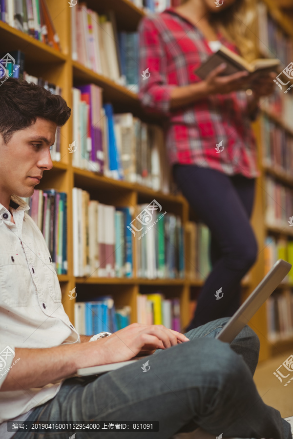 在图书馆地板上工作的男学生