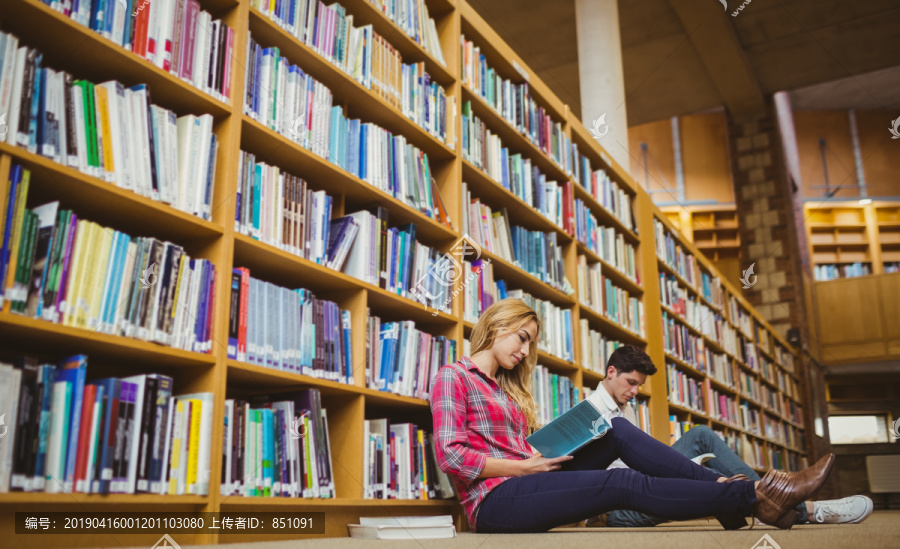 同学靠在图书馆的书架上看书