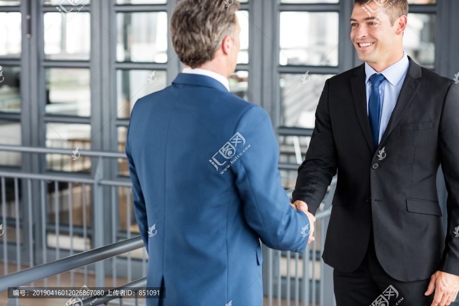 两个微笑的商人在办公室里握手