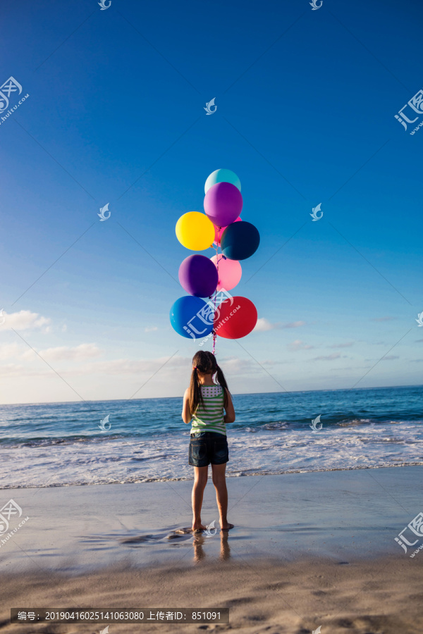 可爱的小女孩在海滩上拿着气球