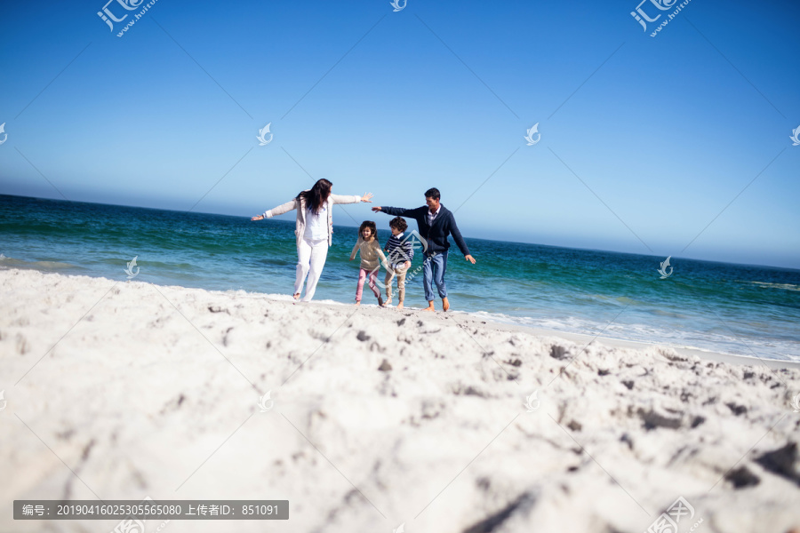 海滩上伸出双臂的可爱家庭