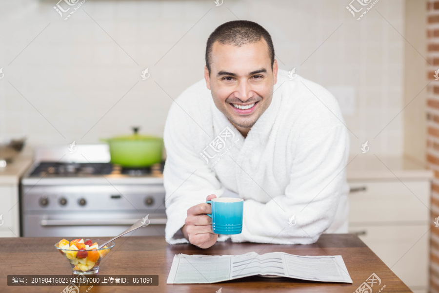 男人在厨房里看杂志喝咖啡