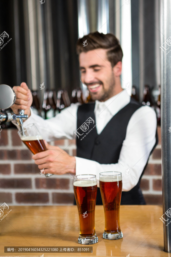 酒吧招待在酒吧里倒啤酒