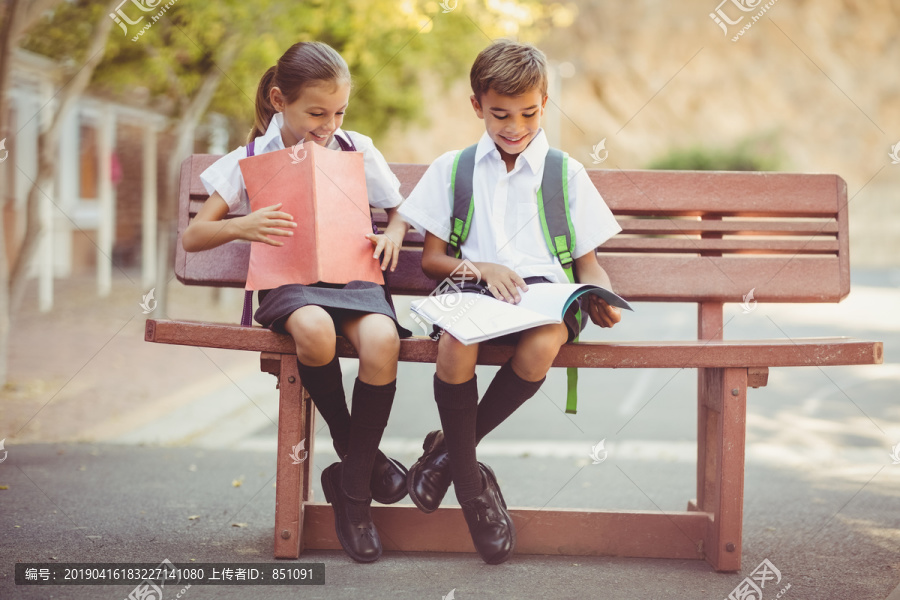 微笑的学生坐在长椅上看书
