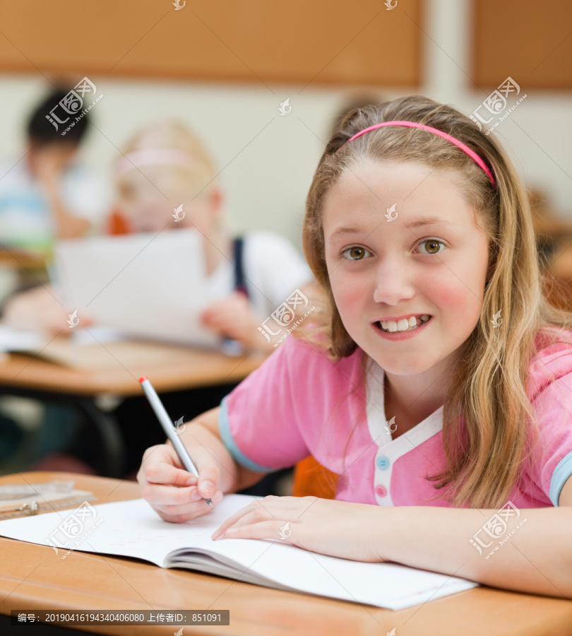 坐在桌旁微笑的年轻女学生
