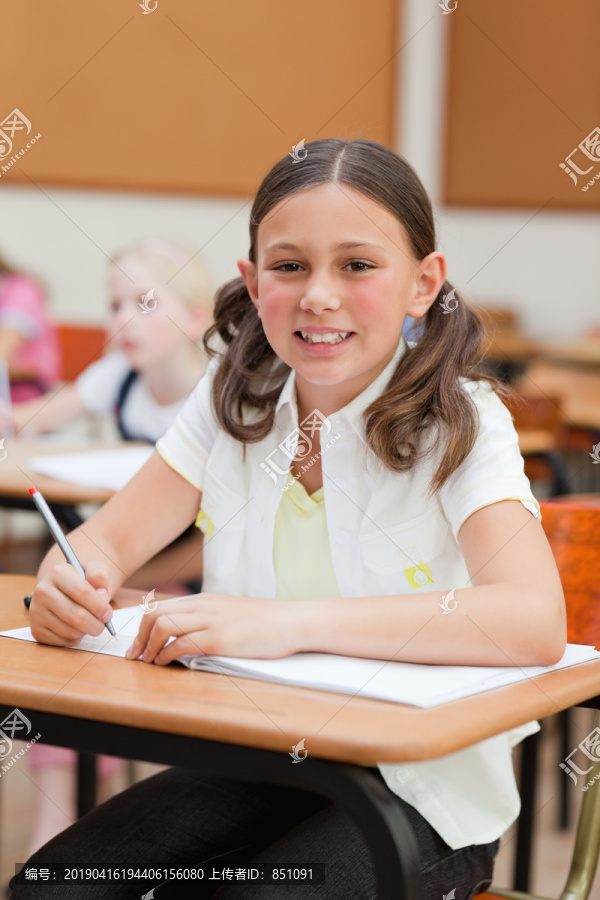 在学校的课桌旁微笑的小女孩