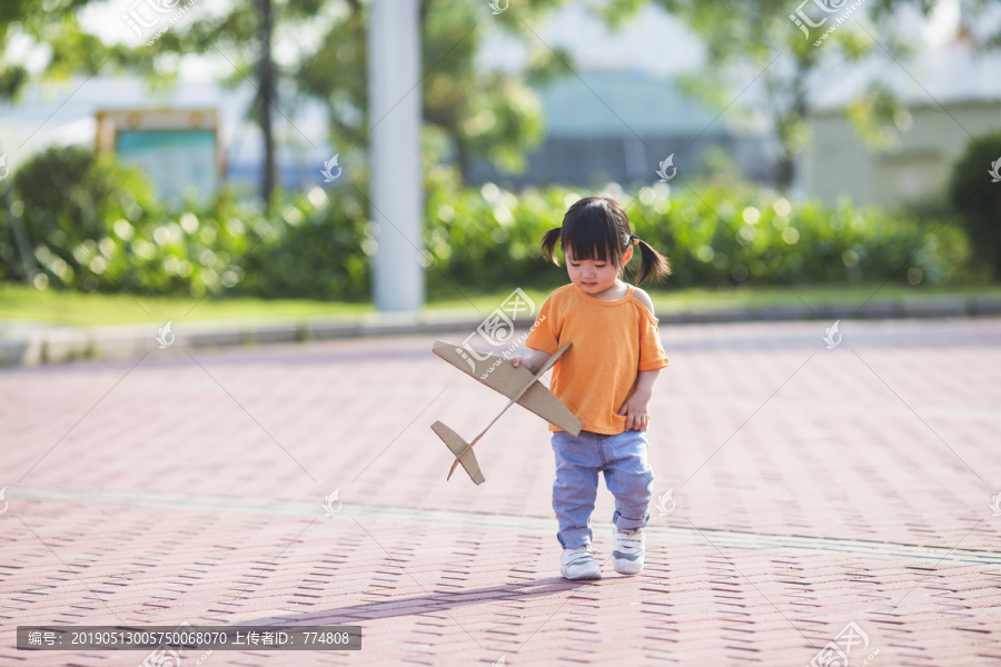 一个女孩子拿着纸飞机在公园玩耍