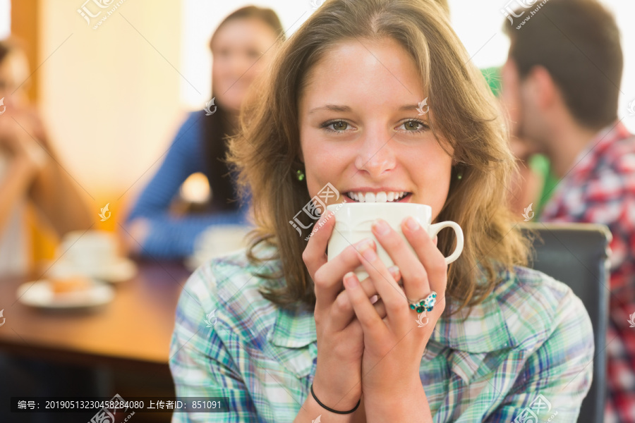 一位微笑的女性在咖啡店喝咖啡