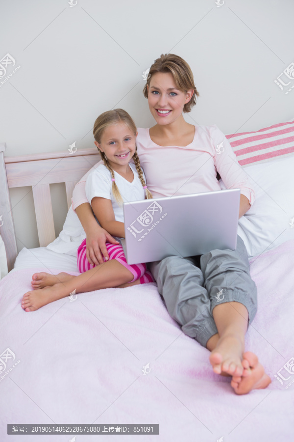 妈妈和女儿在卧室里用平板电脑