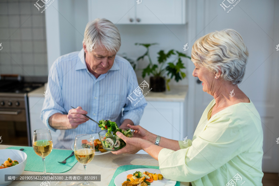 在厨房准备蔬菜沙拉的老夫妇