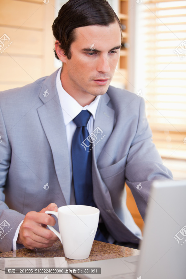 在电脑上放咖啡的年轻商人