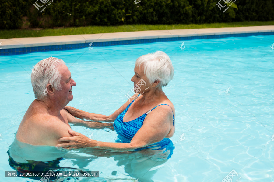 快乐的老年夫妇在游泳池里跳舞