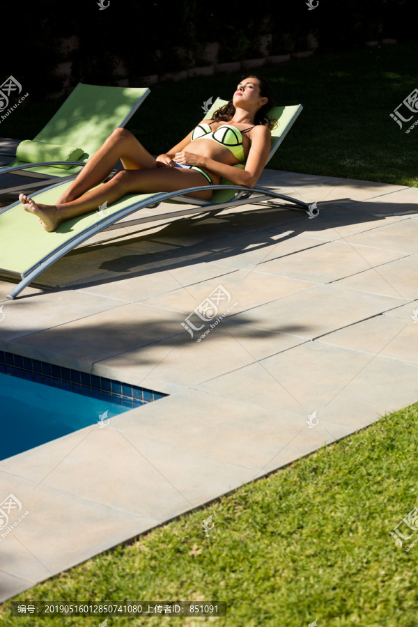 在游泳池边的躺椅上休息的女人