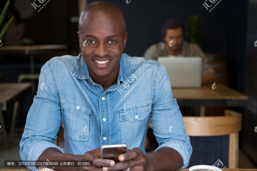 年轻人在咖啡店的木桌上用手机