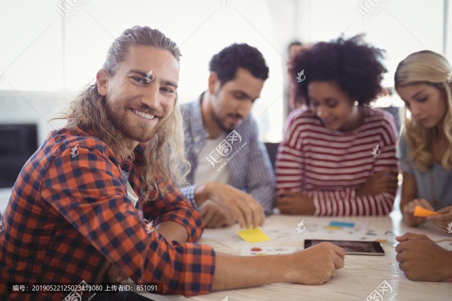 与同事坐在办公桌旁年轻商人