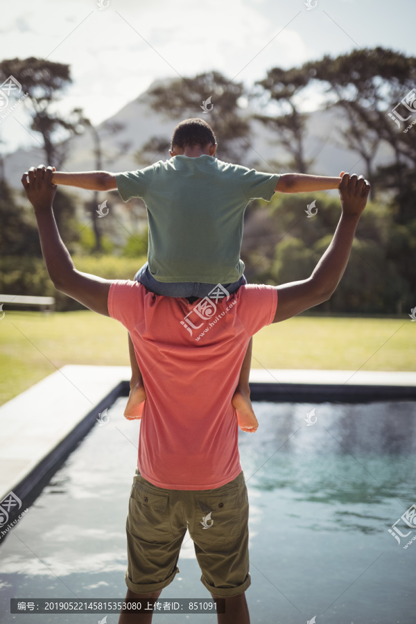 父亲把儿子扛在池边的肩膀上