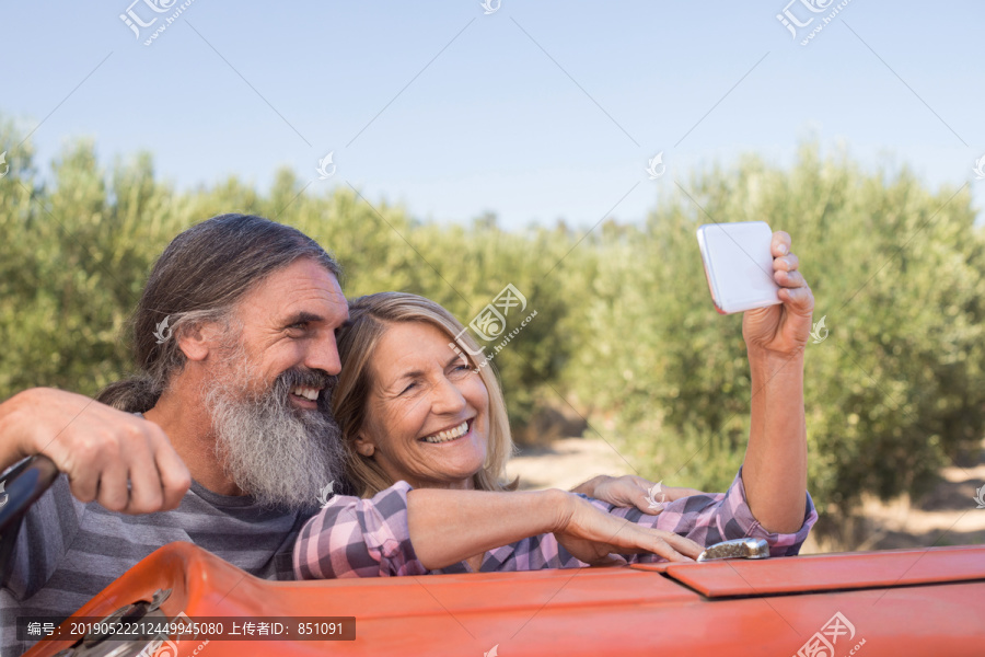 在橄榄农场从手机上拍自拍的夫妻