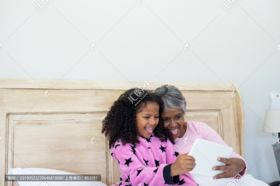 奶奶和孙女在卧室的平板上自拍
