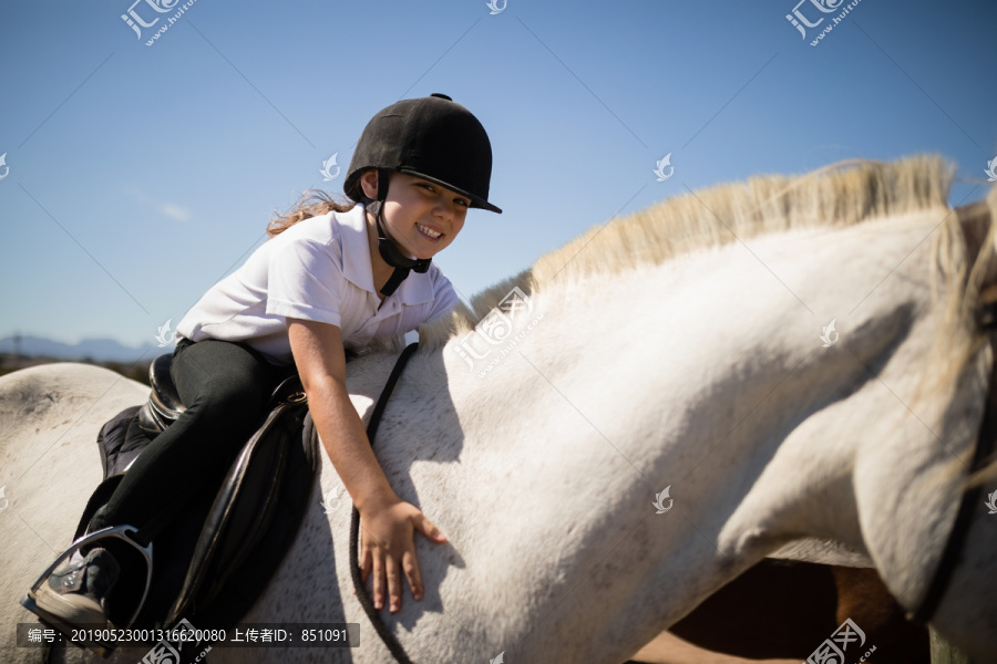 微笑的女孩在牧场里拥抱着白马