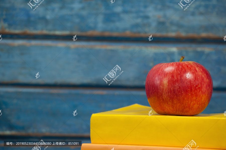 蓝木背景下的一堆书和苹果