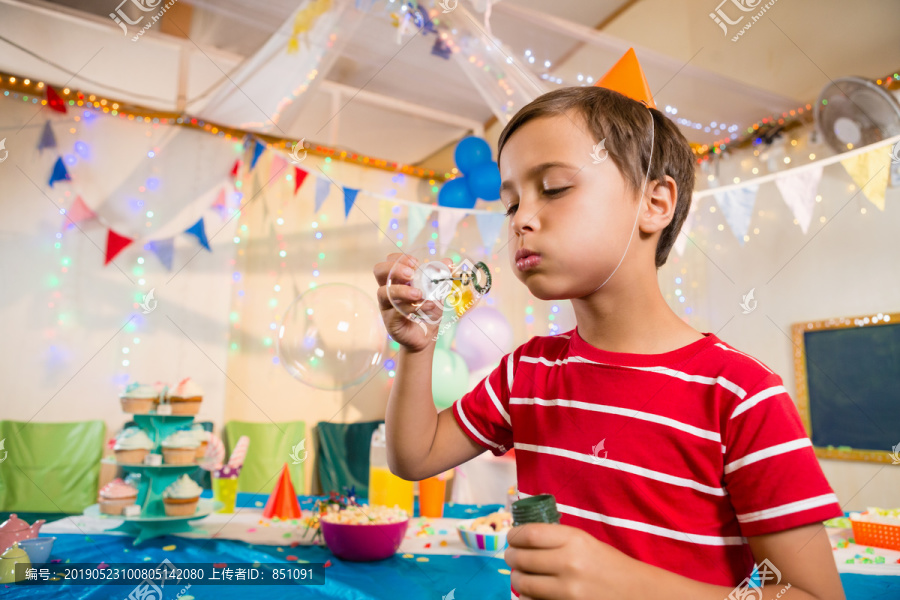 生日聚会上玩泡泡棒的可爱男孩