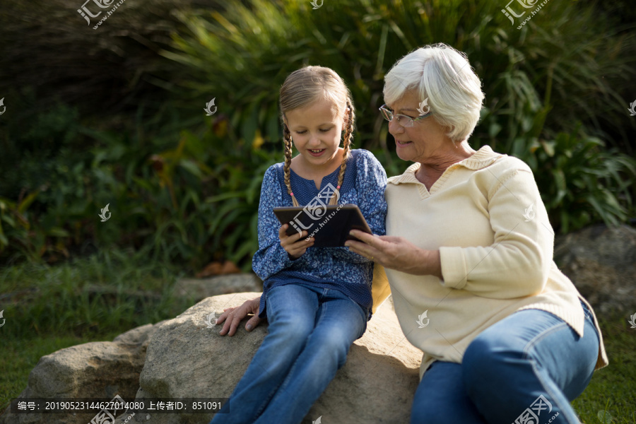 微笑的孙女和祖母在花园里看书