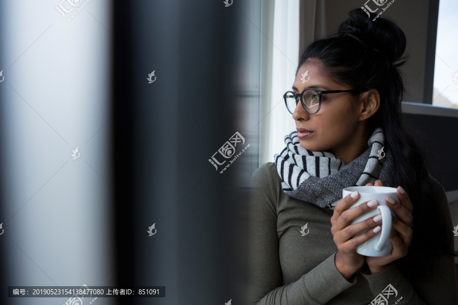 窗口端着咖啡杯的年轻女子