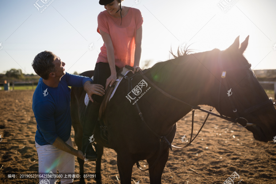 男教练在马镫上调整年轻女子的腿
