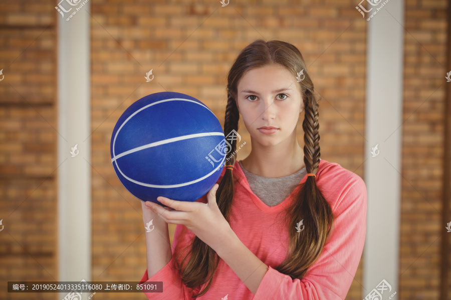 在球场上拿着篮球的女孩