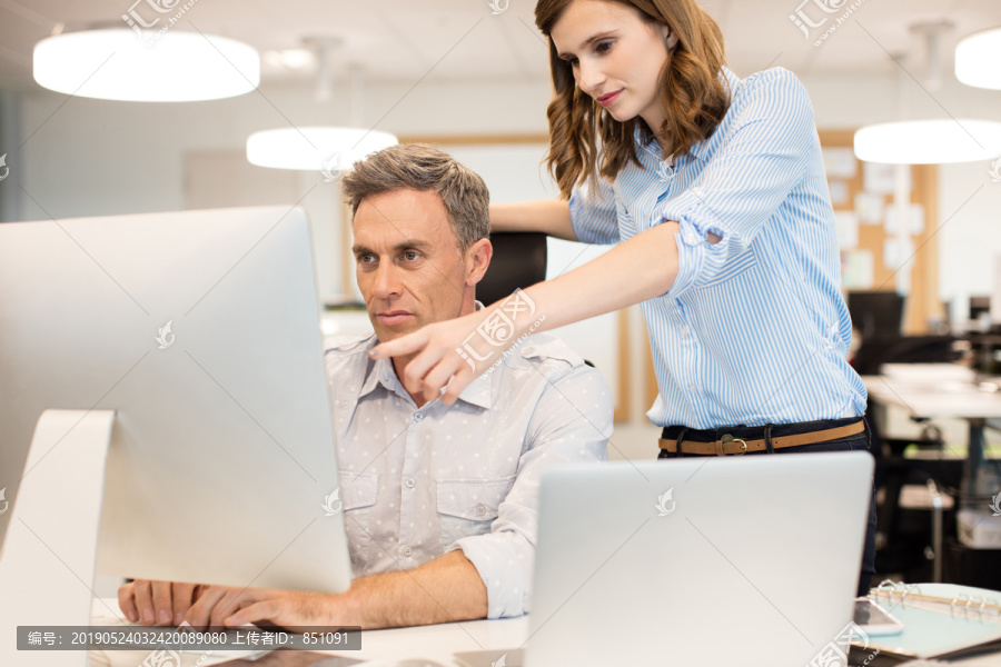 女同事协助商人在办公室使用电脑