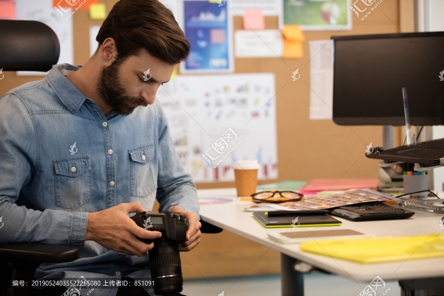在办公桌上使用相机的专业摄影师