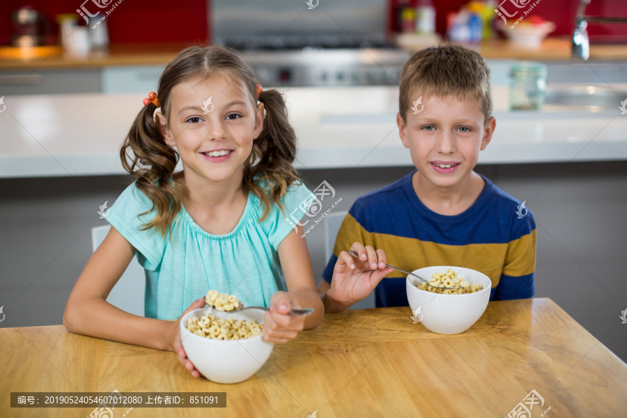微笑的兄妹在厨房吃早餐麦片
