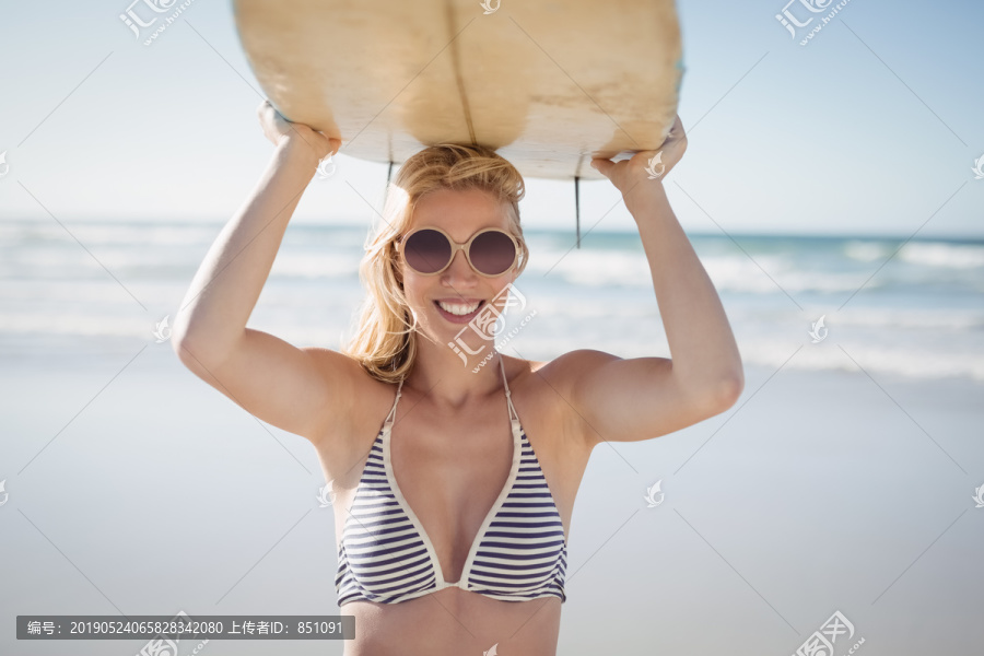 海滩上拿着冲浪板的年轻女性