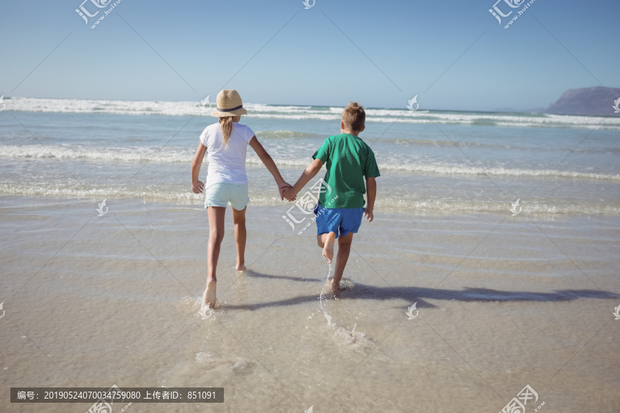 在海滩上奔跑时手牵手的孩童