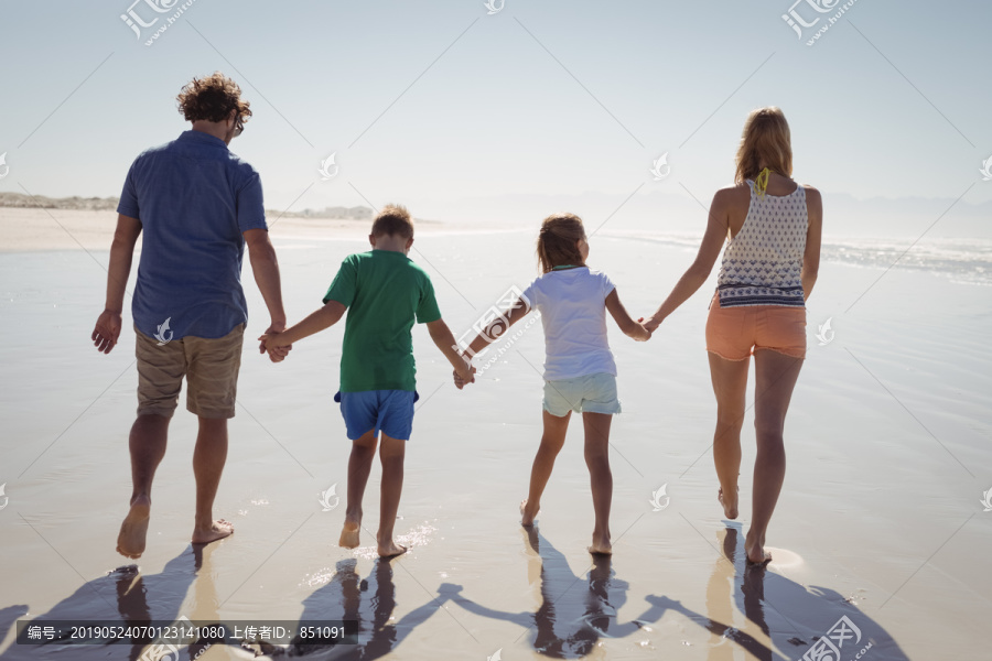 一家人手牵着手站在海滩上的照片
