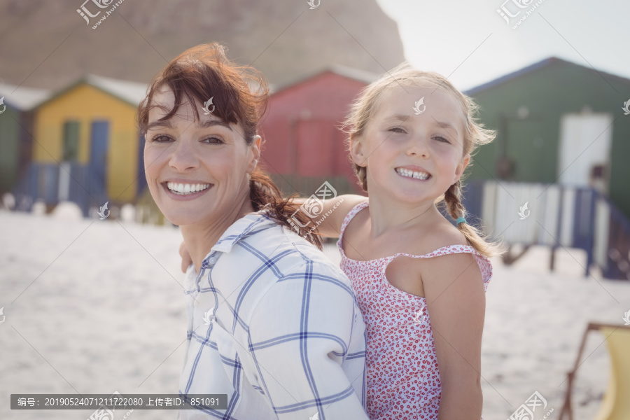 海滩上带女儿的微笑女人