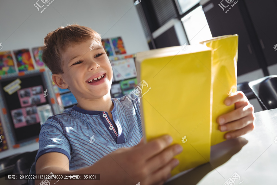 快乐的男孩坐在教室的书桌边读书