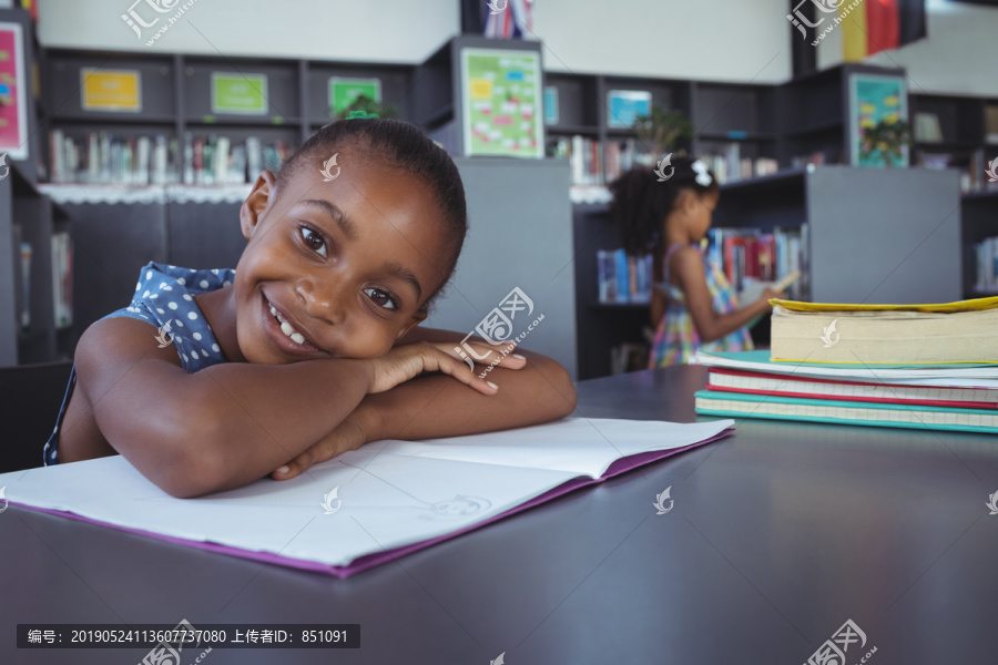 图书馆书桌旁微笑女孩倚书近照
