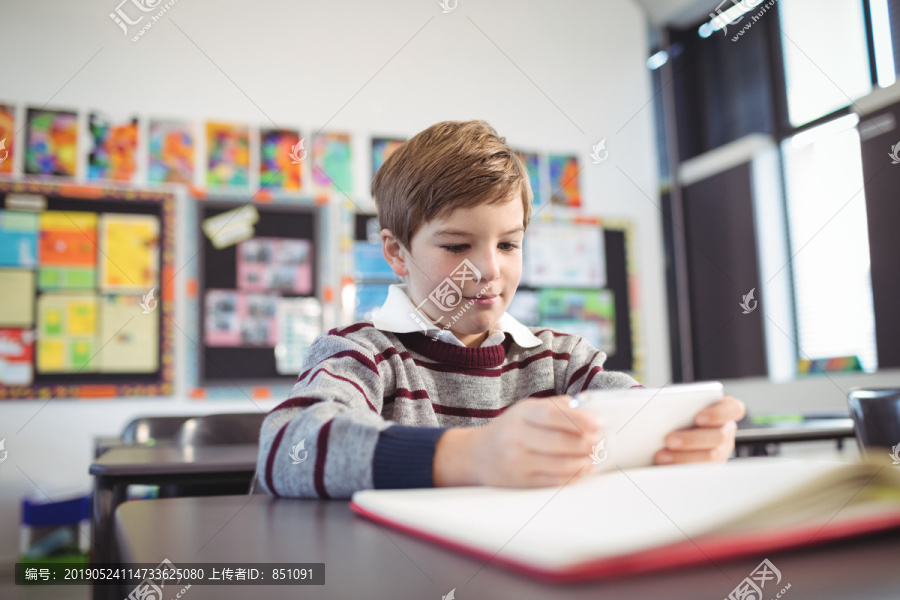 男孩在教室的桌子上用手机