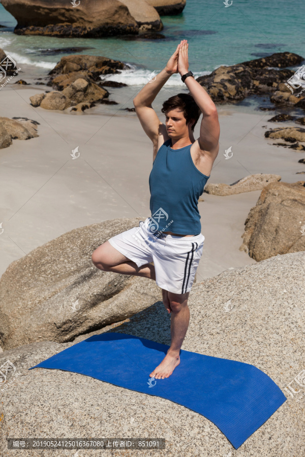 在海岸附近的岩石上做瑜伽的人