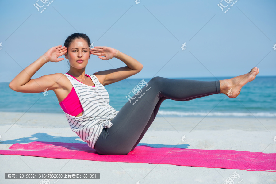 在沙滩垫子上运动的年轻女子
