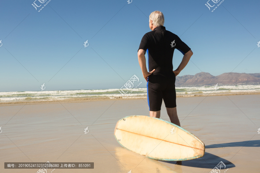 沙滩上站在冲浪板旁的老人画像