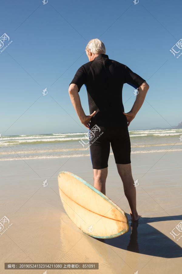 沙滩上站在冲浪板旁的老人画像