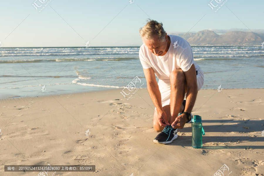 老人在碧空沙滩系鞋带