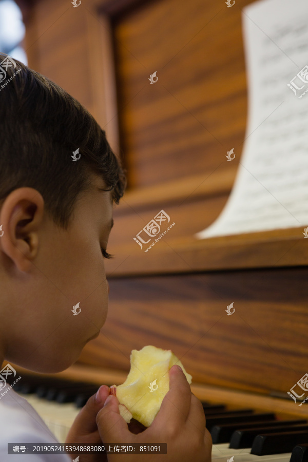 男孩靠着钢琴吃苹果的特写镜头